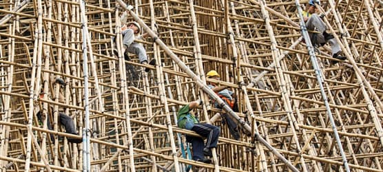  a large bamboo scaffolding structure with several workers climbing and working on it